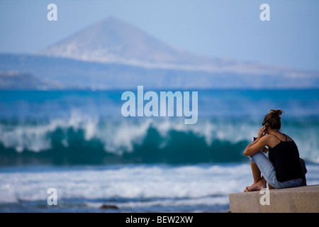 Femme regardant le surfbreak et chatter sur son téléphone portable Banque D'Images