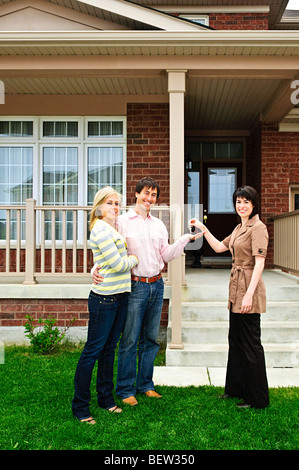 Couple heureux obtenir les clés de maison neuve d'agent immobilier Banque D'Images