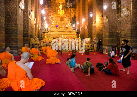 Un moine en prière à l'intérieur d'un temple de Wat Po complexe. Bangkok, Thaïlande Banque D'Images