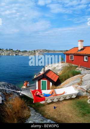 Woman resting in hamac sur Huvudskar Huvudskär Island avec red maison d'été dans l'archipel suédois au sud de Stockholm Banque D'Images