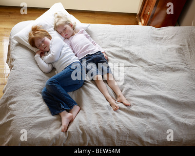 Deux soeurs se coucher dormir sur un lit, elevated view Banque D'Images