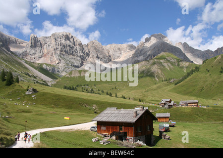 Promenade en famille sur lane près de chalets bois pour la fenaison dans les Dolomites italiennes de l'été Banque D'Images