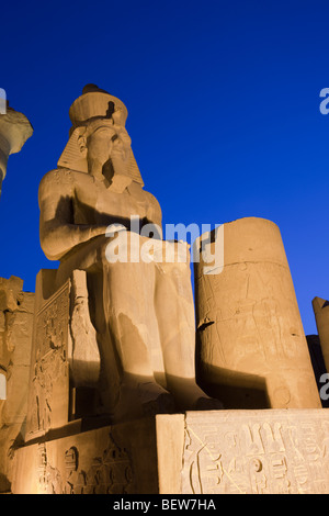 Ramsès II assis lumineux colosse à l'intérieur du temple de Louxor, Louxor, Egypte Banque D'Images