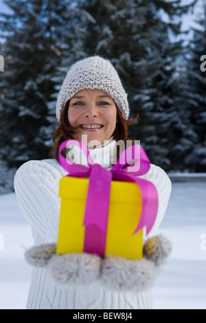 Woman holding Christmas Gift and smiling Banque D'Images