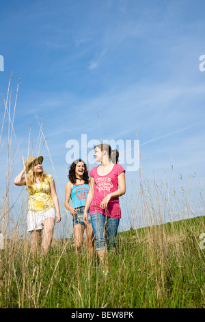 Trois jeunes filles marcher dans un pré, low angle view Banque D'Images