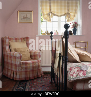 Fauteuil rose vérifié en rose cottage chambre avec fenêtre jaune vérifié sur aveugle Banque D'Images