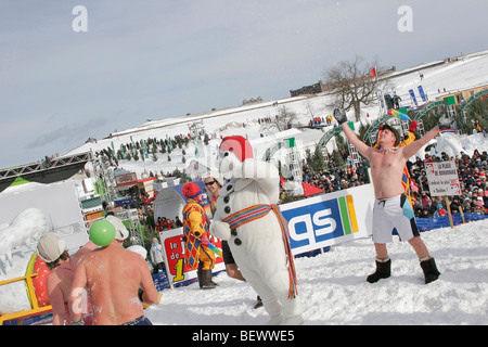 Les fêtards jouer dans la neige, vêtus de costumes de bain, avec mascot Bonhomme Carnaval en hiver au Québec Banque D'Images