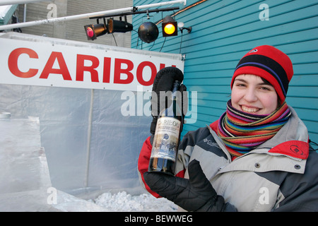 Jeune femme montre une bouteille de Caribou, boisson officielle du Carnaval d'hiver est fabriqué à partir de vin de porto, l'alcool et le sirop. Banque D'Images