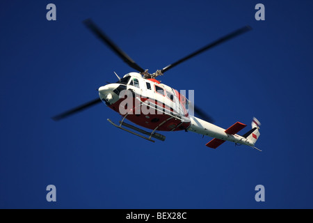 En hélicoptère vol ciel bleu profond. Les couleurs de la Garde côtière canadienne. Banque D'Images