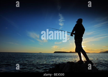 L'homme pêche sur le coucher du soleil Banque D'Images