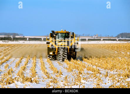 Un TerraGator à l'application de chaux sur un couvert de neige en hiver ; un champ de maïs est en train d'éthanol en passant par en arrière-plan / Illinois, États-Unis Banque D'Images