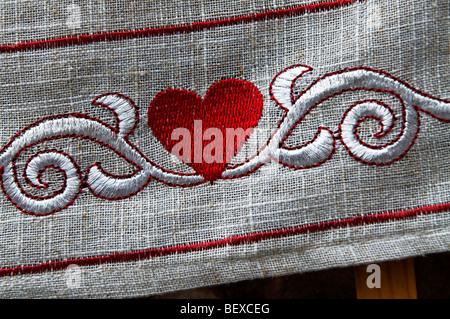 TEXTURE DE TISSU BRODERIE COEUR AMOUR Fermer vue sur coeur rouge brodé sur la bordure de nappe en lin Banque D'Images