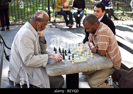 Deux hommes noirs se concentrant intensément, l'un avec le vitiligo, jouer aux échecs dans le parc de l'Hôtel de ville de New York par un beau jour d'automne Banque D'Images