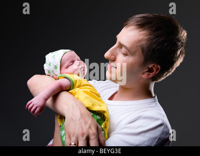 Studio photo de jeune père, avec ses 14 jours d'âge nouveau-né fille sur fond noir Banque D'Images