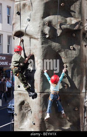 Les enfants l'apprentissage de l'Escalade sur mur d'escalade artificielle en plein air dans un événement de collecte de fonds. England UK Banque D'Images