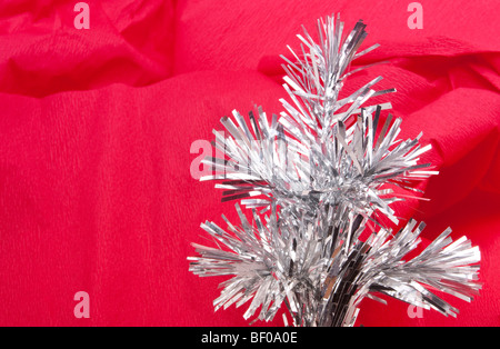 Résumé de guirlandes d'argent papier crépon rouge contre l'image de fond de Noël Banque D'Images