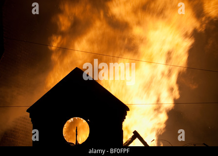 Apex de bâtiment de l'usine en feu dans la nuit avec des flammes en arrière-plan Banque D'Images