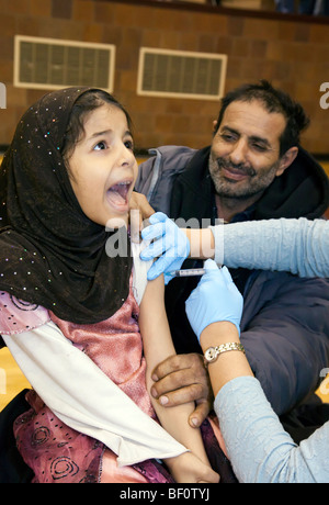 Hamtramck, au Michigan - un travailleur de la santé vaccine une fille contre le H1N1 de la grippe porcine pour son papa montres. Banque D'Images