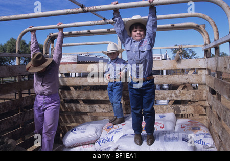 Les garçons  + fille, enfants, cowboys, chapeaux Stetson correspondant shirts et jeans, jouer dans l'arrière du chariot lors de rodeo, Queensland Australie Banque D'Images