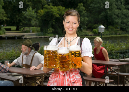 Une femme allemande Traditionnellement vêtus servant de la bière dans un café en plein air Banque D'Images