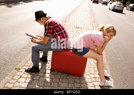 Un jeune couple avec une valise et une carte Banque D'Images