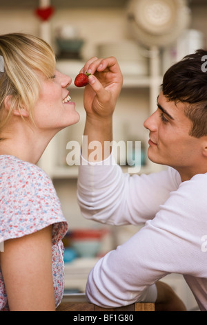 Un jeune homme tenant une fraise indus pour une jeune femme Banque D'Images