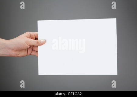 Une main tenant une feuille de papier blanc Banque D'Images