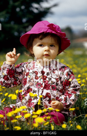 Faustine 16 mois jouant dans un champ de fleurs sauvages jaune Banque D'Images