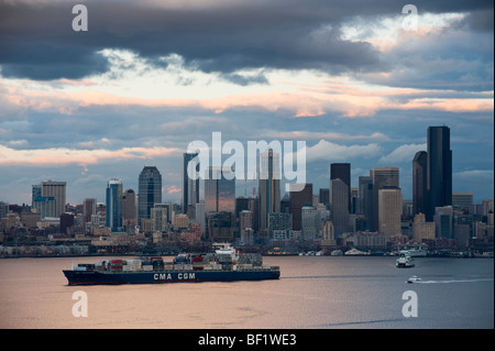 Au coucher du soleil, un porte-conteneurs navigue hors de la baie Elliott et le front de mer de Seattle, Washington. Nuage spectaculaire et l'éclairage. Banque D'Images