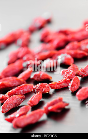 Baies de goji séchées rouge éparpillés sur une table Banque D'Images