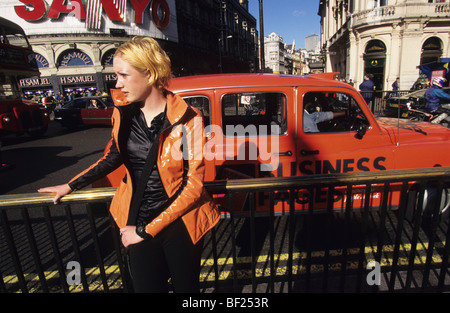 Fille en veste orange et orange taxi, Piccadilly Circus, ville de Londres. Angleterre, Royaume-Uni, Grande Bretagne, Europe Banque D'Images