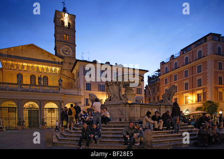 Les gens assis à une fontaine à Piazza Sta Maria dans la soirée, le Trastevere, Rome, Italie, Europe Banque D'Images