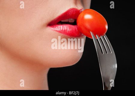 Close-up of a woman eating une tomate cerise Banque D'Images