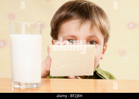 Portrait d'un garçon avec une barre de chocolat blanc et un verre de lait Banque D'Images