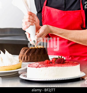 Mid section view of a female chef cerise d'un gâteau Banque D'Images