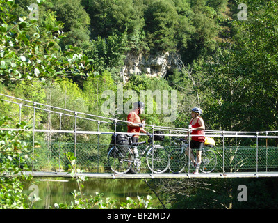 Deux cyclistes reposant sur un pont en fer sur la rivière Cares dans le nord de l'Espagne Banque D'Images