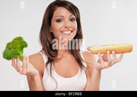 Femme de choisir entre le brocoli et un hot-dog Banque D'Images