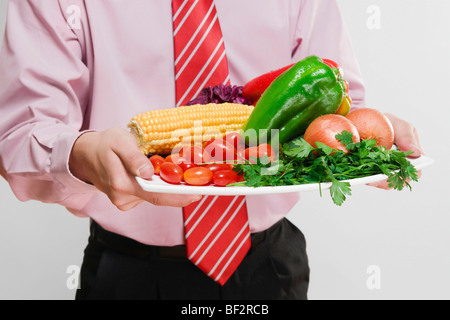 Businessman holding un plat de légumes frais Banque D'Images