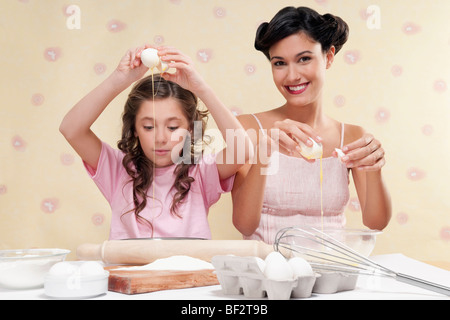 Femme avec sa fille casser des œufs Banque D'Images