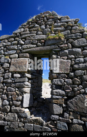 Regarder à travers une fenêtre d'une maison de pierre abandonnée une ancienne église sur l'île de Omey, Connemara, Irlande Banque D'Images