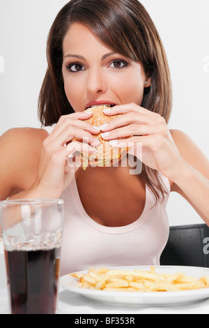 Portrait d'une femme mangeant un hamburger Banque D'Images