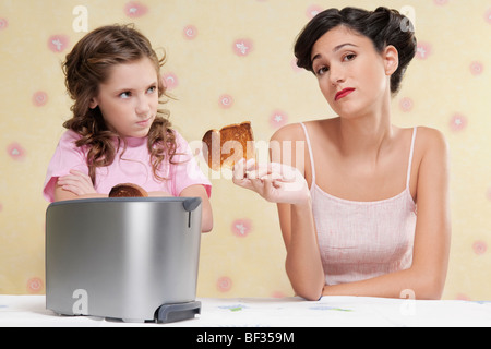 Femme de donner à sa fille un pain brûlé Banque D'Images