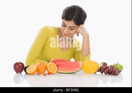 Femme regardant une rangée d'un assortiment de fruits frais Banque D'Images