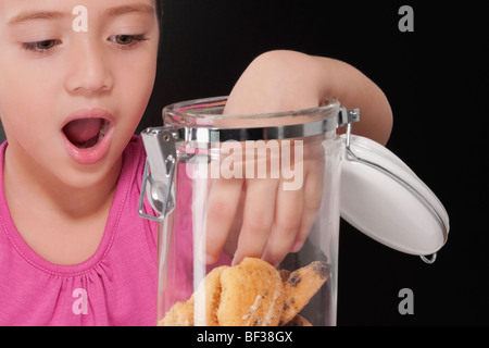 Fille de mettre sa main dans un cookie jar Banque D'Images