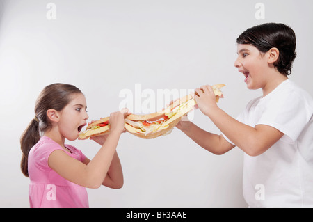 Fille et garçon manger un sandwich sous-marin Banque D'Images