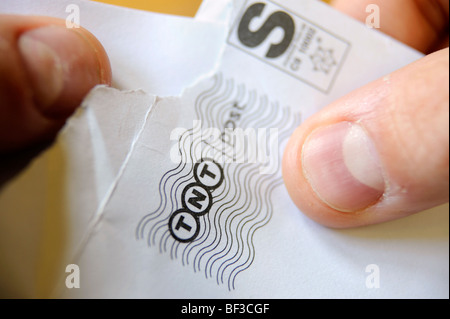 Un homme ouvre une lettre livrée par TNT Banque D'Images