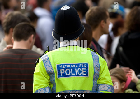 Un agent de police métropolitaine de Londres dans une veste jaune haute visibilité et le casque en service Banque D'Images