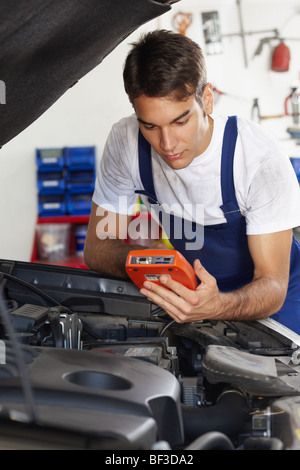 Mechanic S'appuyant sur capot avec équipement testeur Banque D'Images