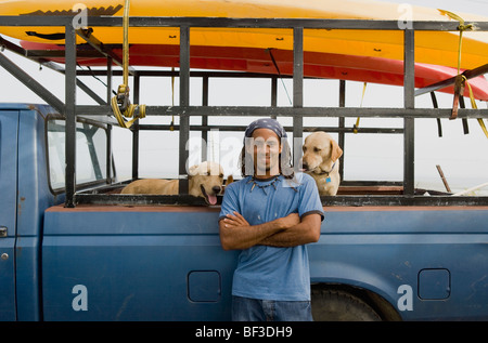 Hispanic man with dog leaning against truck Banque D'Images