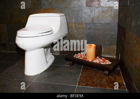 La cuvette des toilettes avec une bougie dans la salle de bains Banque D'Images